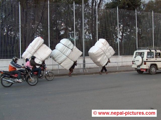 Three men carrying huge loads